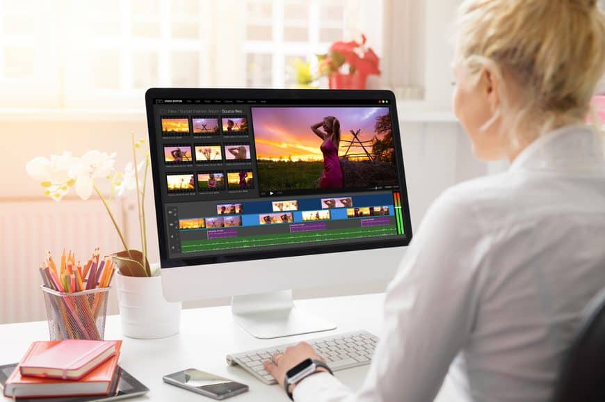 Une femme derrière un ordinateur qui fait du montage vidéo.